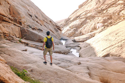 Rear view of man walking on mountain canyon, fuerteventura, spain