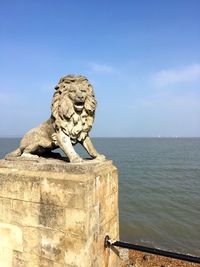 Statue by sea against sky