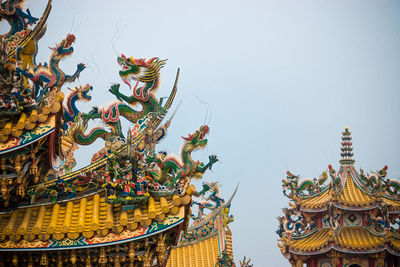 Low angle view of statue against temple against clear sky