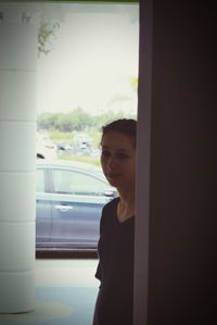 Young woman looking through window