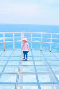 Rear view of woman standing by sea against sky