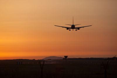 Airplane flying over field against sky