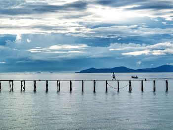 Wooden posts in sea against sky