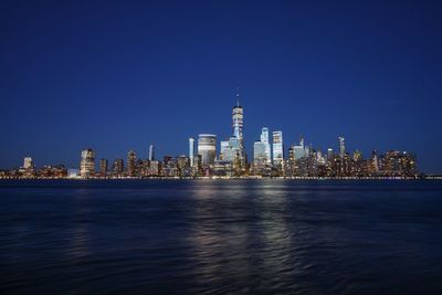 Sea by modern buildings in city against sky