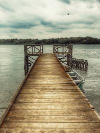 Pier on lake against cloudy sky