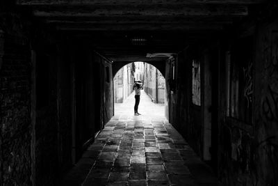 Distant view of woman standing on footpath seen through archway