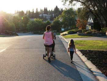 Rear view of mother and daughter walking on road