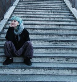 Portrait of woman sitting on staircase in city