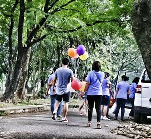 Rear view of people relaxing on footpath at park