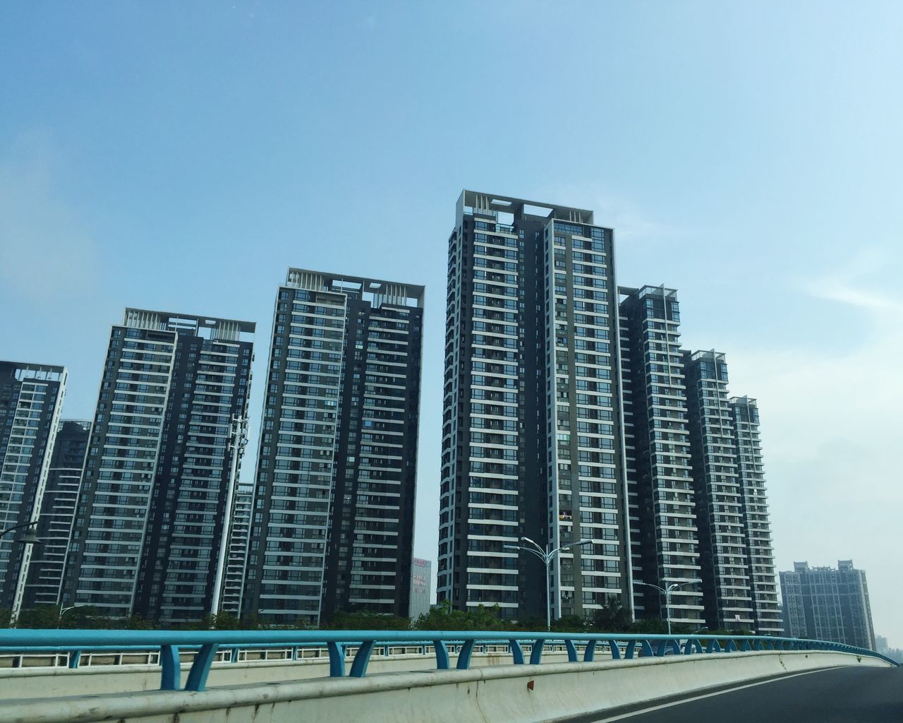 architecture, built structure, building exterior, clear sky, low angle view, city, building, blue, copy space, sky, outdoors, day, modern, railing, no people, office building, sunlight, city life, residential building, skyscraper