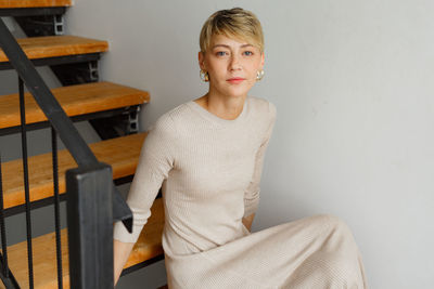 Portrait of young woman standing against wall