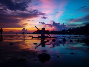 Silhouette person on beach against sky during sunset