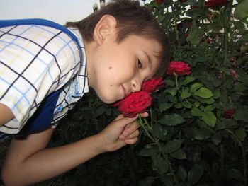 Teenage boy holding red rose in garden