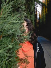 Young woman looking away against tree