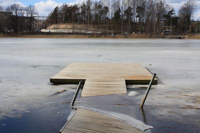 Empty bench by frozen trees in park during winter