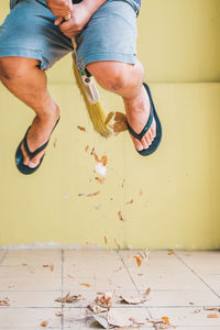 Low section of man jumping with broom