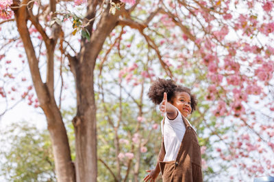 Girl standing by tree against plants