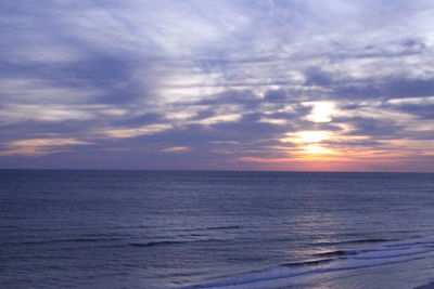 Scenic view of sea against cloudy sky at sunset