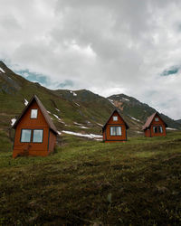 House on field by houses against sky