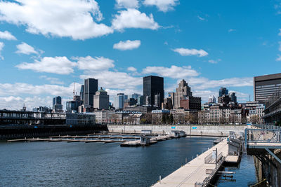 River by modern buildings against sky in city