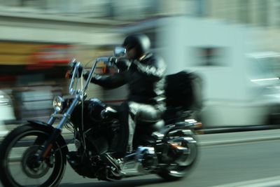 Blurred motion of people riding motorcycle on road