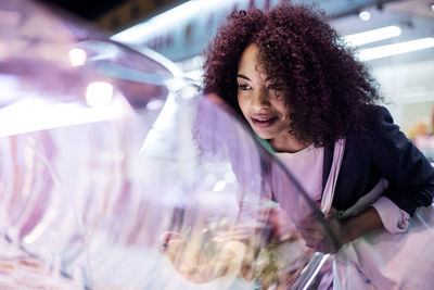 Woman looking at display cabinet while shopping in market