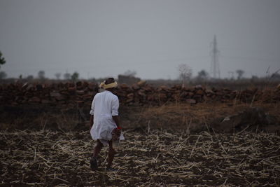 Rear view of man walking on field at dusk