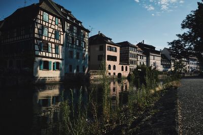 Buildings by lake against sky in city