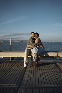 Friends embracing each other while sitting on bench