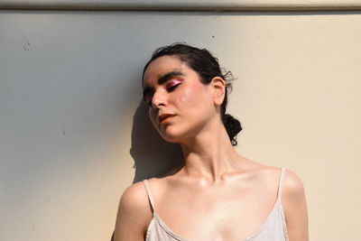 Portrait of young human looking away against wall