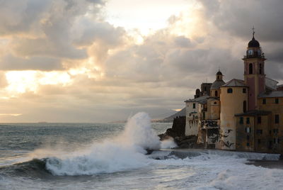 Sea waves splashing on shore against buildings