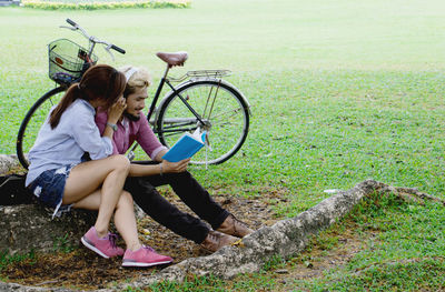 Couple reading book while sitting in park