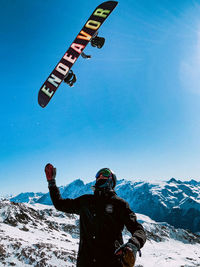 Low section of man on snowcapped mountain against clear sky