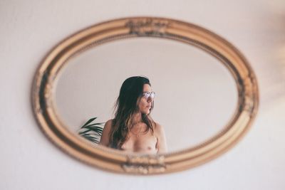 Portrait of woman with reflection against wall