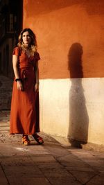 Portrait of woman standing against wall