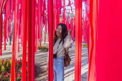 Full length of woman standing against red wall