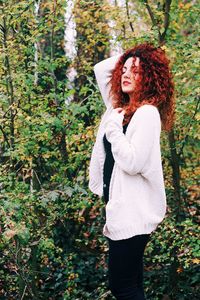 Portrait of smiling woman standing against trees