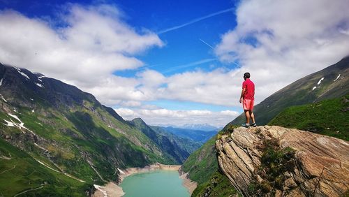 Rear view of man standing on mountain against sky