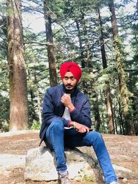 Full length portrait of young man sitting outdoors