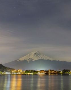 Scenic view of lake by mountains against sky at night