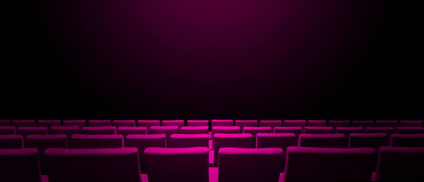 View of empty chairs in row against black background