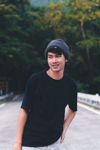 Portrait of smiling boy standing against waterfall