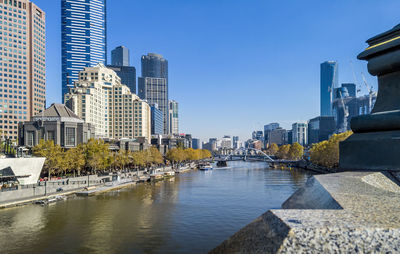Modern buildings by river against clear sky