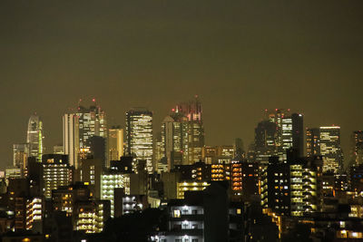 Illuminated cityscape against clear sky at night