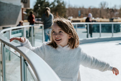 Young girl holding on to rail while learning how to ice skate