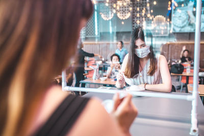 Midsection of woman holding mobile phone while sitting on table