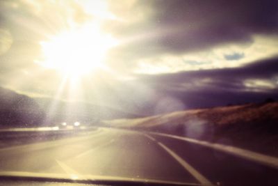 Cars on road against cloudy sky