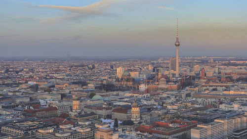 Fernsehturm amidst cityscape against sky during sunset