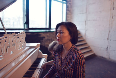 Close-up of young woman sitting by piano