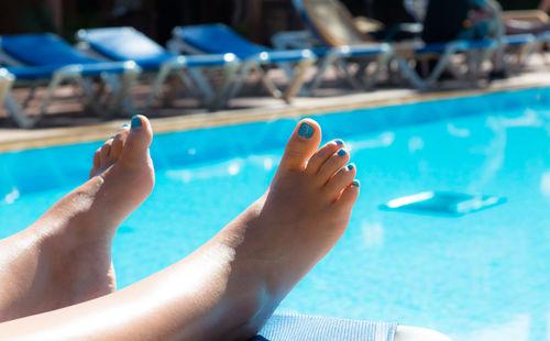 Low section of woman relaxing at swimming pool